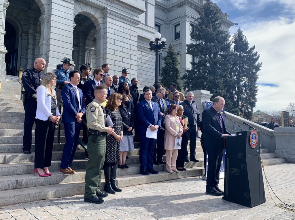 Colorado Department of Public Safety employees standing behind Governor Polis on the steps of the state capitol