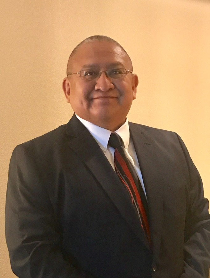 Headshot of Arron Julian a native american man with glasses wearing a suit and tie