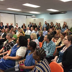 a large group of CDPS employees sits in rows in a room listening