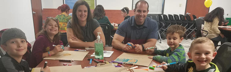 Family of mom, dad and four boys colors on paper bags at a table