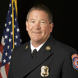 photo of mike morgan in a dark dress firefighter uniform and a badge