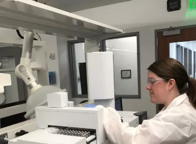 A woman in a white lab coat works with lab equipment