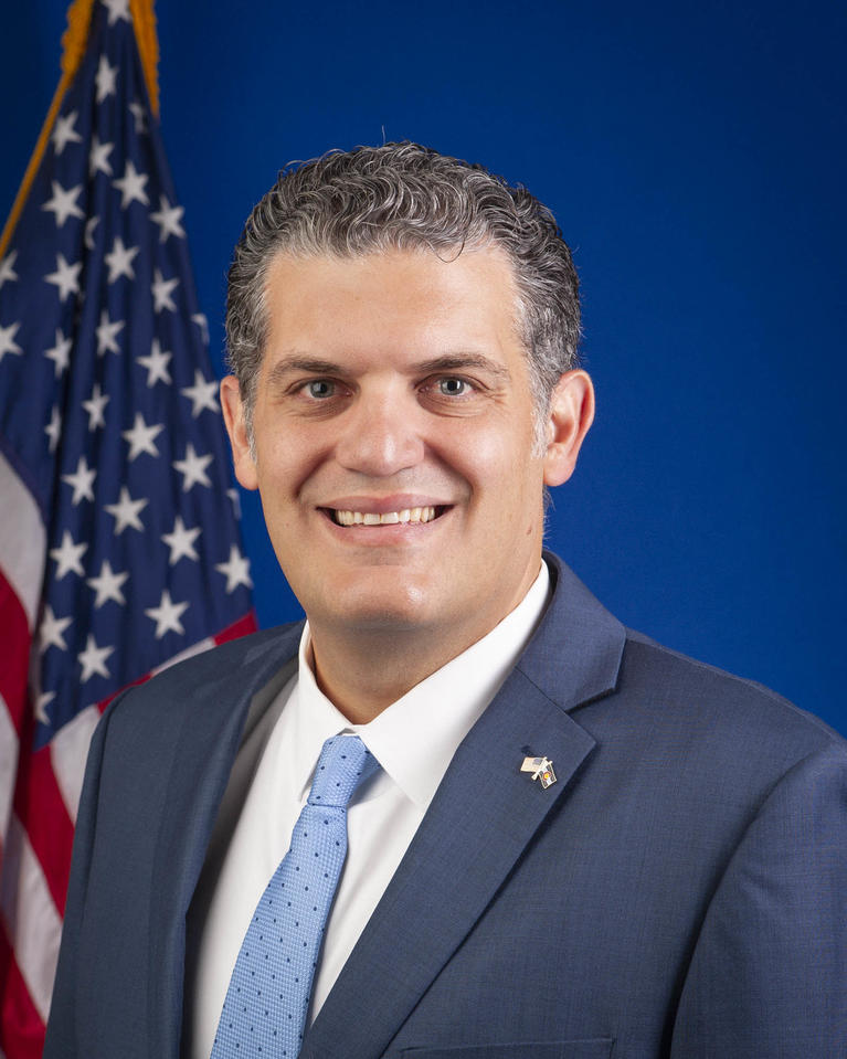 Picture of Matt Lunn wearing a blue suit, white shirt, and light blue tie