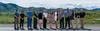 A dozen CDPS employees, both men and women, of different races heights and clothing styles stand in a line